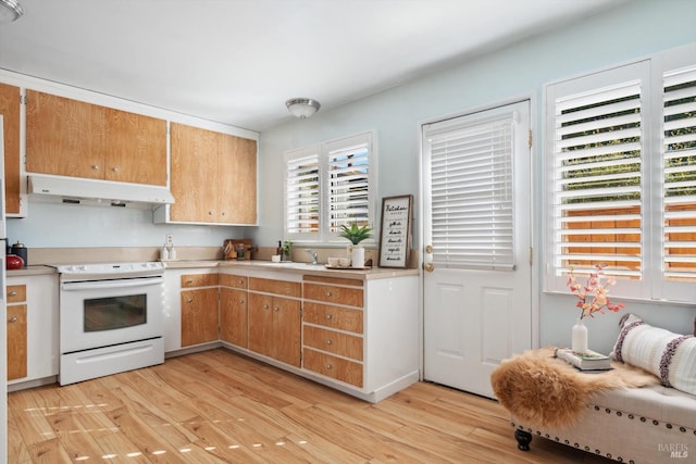 kitchen with under cabinet range hood, light wood-style flooring, light countertops, and white range with electric cooktop