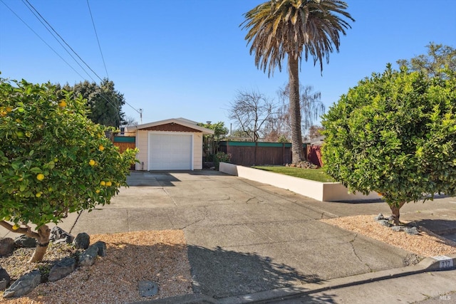 view of front facade featuring an outdoor structure, driveway, a detached garage, and fence