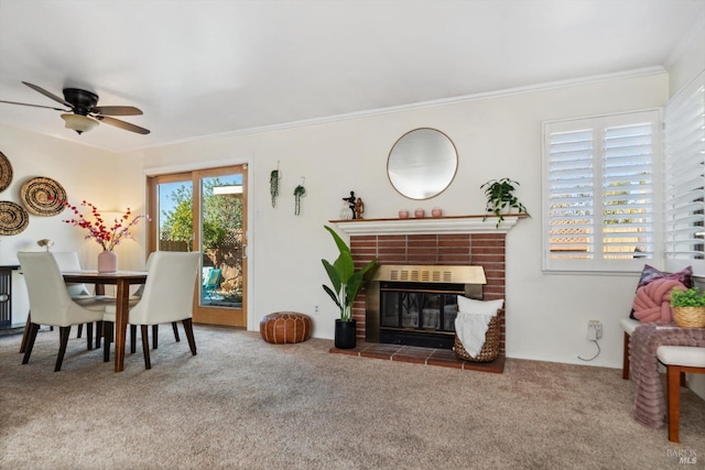 dining area featuring ceiling fan, ornamental molding, a brick fireplace, and carpet flooring