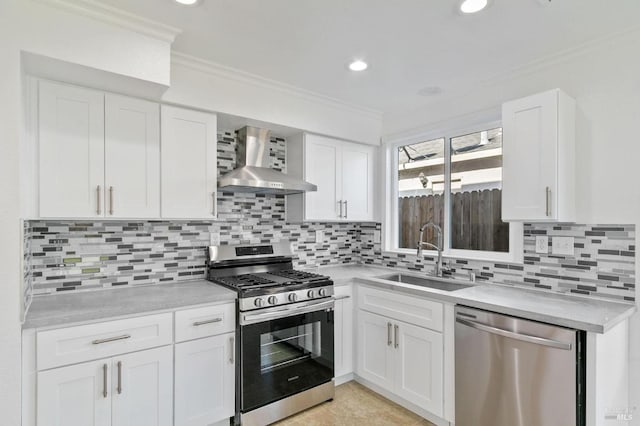 kitchen featuring sink, crown molding, appliances with stainless steel finishes, white cabinetry, and wall chimney exhaust hood