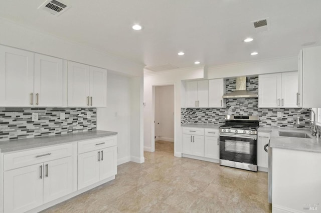 kitchen featuring white cabinets, sink, gas stove, and wall chimney range hood