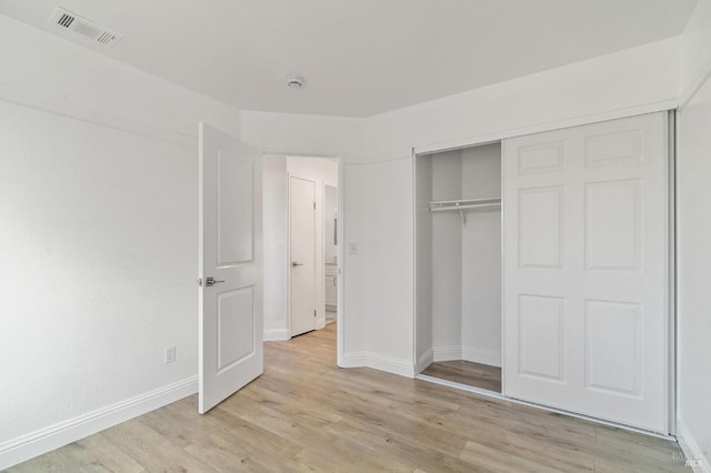 unfurnished bedroom with light wood-type flooring and a closet