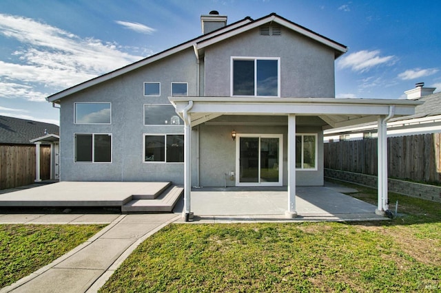 back of house featuring a deck, a patio area, and a lawn