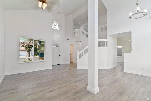 unfurnished living room featuring light hardwood / wood-style flooring, a chandelier, and a high ceiling