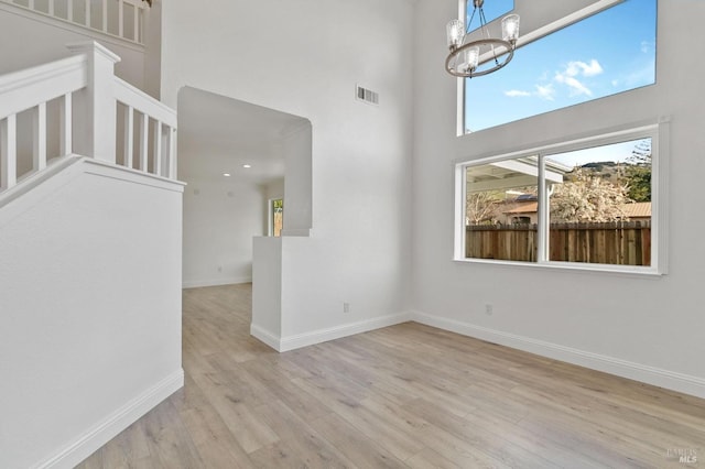 interior space featuring an inviting chandelier, a towering ceiling, and light hardwood / wood-style flooring