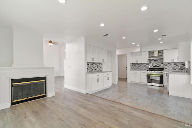 kitchen featuring white cabinetry, light hardwood / wood-style flooring, stainless steel range with gas stovetop, and wall chimney exhaust hood