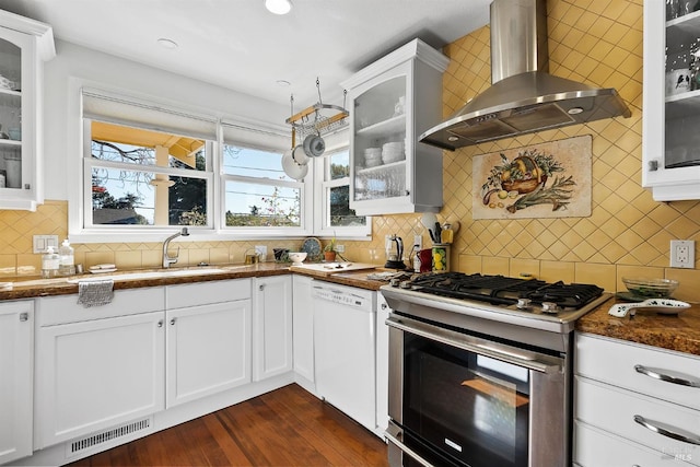 kitchen with white dishwasher, white cabinets, stainless steel gas range oven, and wall chimney exhaust hood