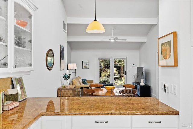 kitchen featuring pendant lighting, ceiling fan, vaulted ceiling with beams, light stone counters, and white cabinets