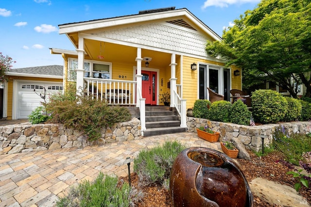 view of front facade featuring an outdoor fire pit, covered porch, and a garage