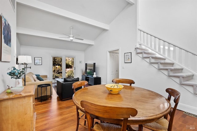 dining space with ceiling fan, light hardwood / wood-style floors, and vaulted ceiling with beams