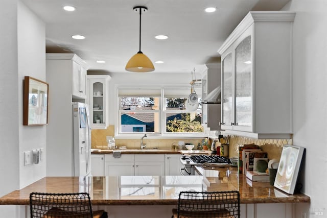 kitchen with sink, white cabinetry, hanging light fixtures, white fridge with ice dispenser, and decorative backsplash