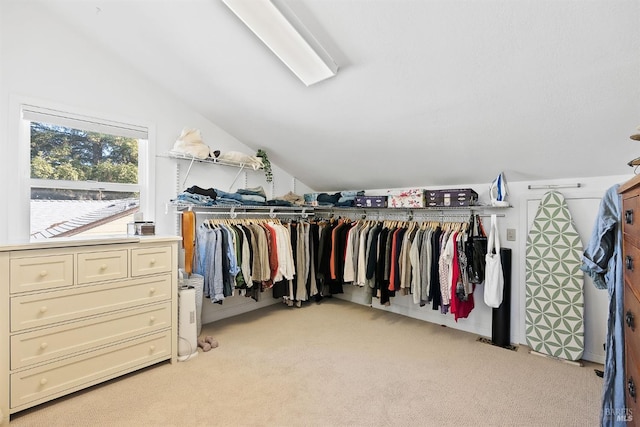 walk in closet with vaulted ceiling and light carpet