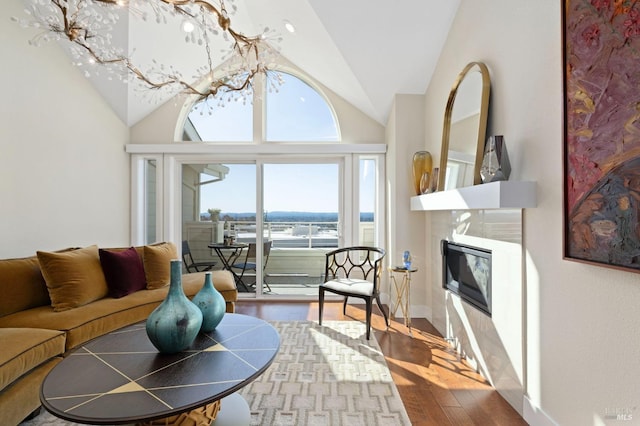 living area with vaulted ceiling, a notable chandelier, a fireplace, and wood finished floors