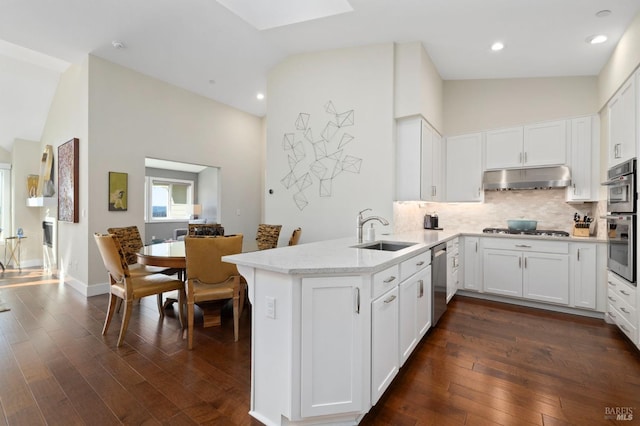kitchen featuring a sink, under cabinet range hood, appliances with stainless steel finishes, a peninsula, and white cabinetry