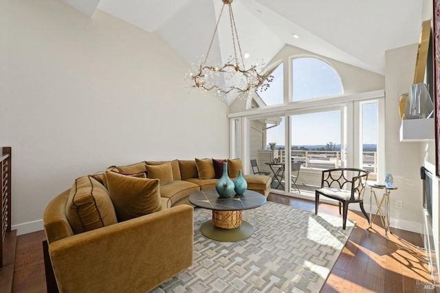 living room with an inviting chandelier, baseboards, high vaulted ceiling, and wood finished floors