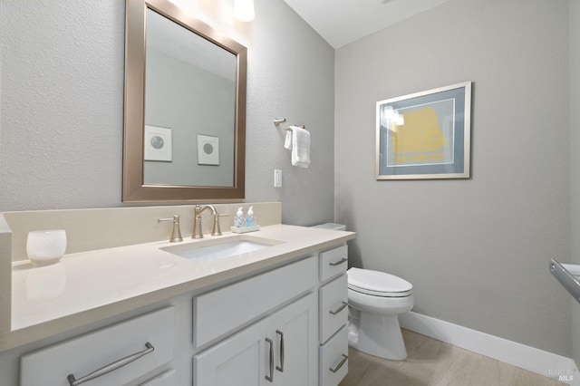 bathroom featuring toilet, vanity, and baseboards