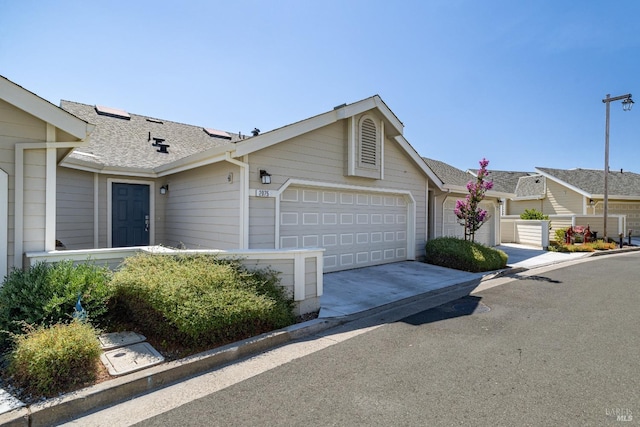 single story home with a garage, driveway, and roof with shingles