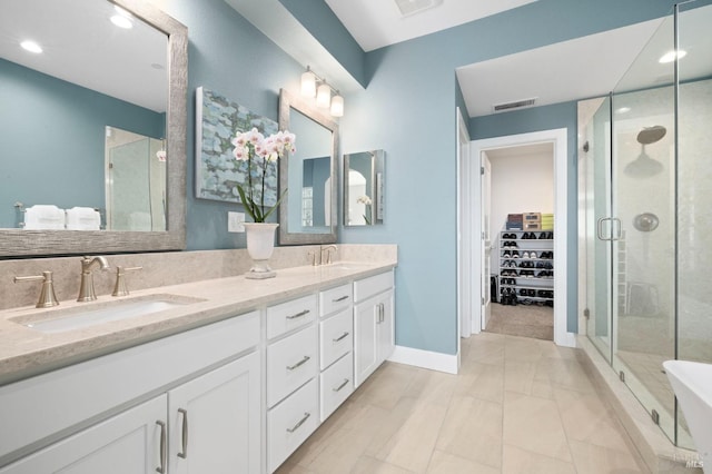 full bath with a sink, double vanity, a stall shower, visible vents, and a walk in closet