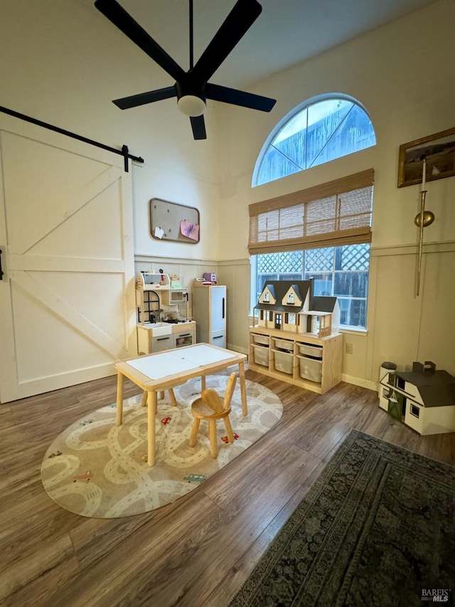 sitting room featuring dark wood-type flooring, ceiling fan, and a barn door