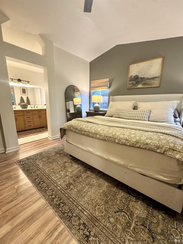 bedroom with lofted ceiling, connected bathroom, ceiling fan, and light hardwood / wood-style flooring