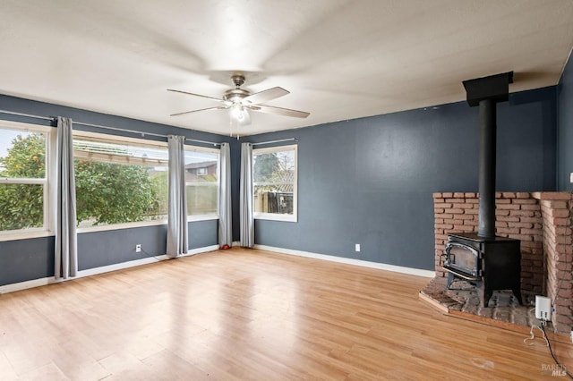 unfurnished living room with light hardwood / wood-style flooring, ceiling fan, and a wood stove