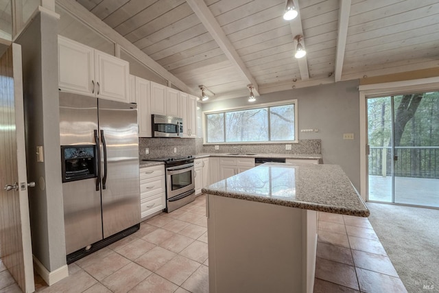 kitchen featuring appliances with stainless steel finishes, white cabinetry, vaulted ceiling with beams, backsplash, and light stone countertops