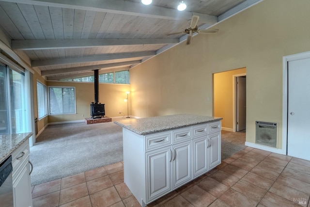 kitchen featuring heating unit, white cabinetry, a wood stove, a center island, and light carpet