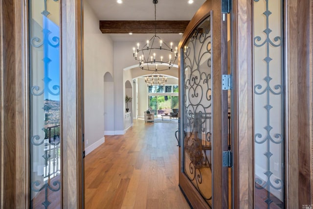 entrance foyer featuring an inviting chandelier, hardwood / wood-style flooring, and beamed ceiling