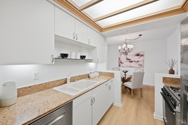 kitchen with pendant lighting, sink, an inviting chandelier, white cabinets, and range with gas cooktop