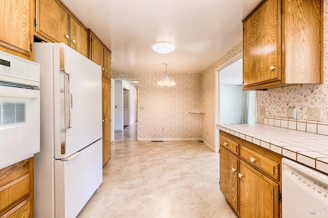 kitchen featuring white appliances, tile counters, decorative light fixtures, and a chandelier