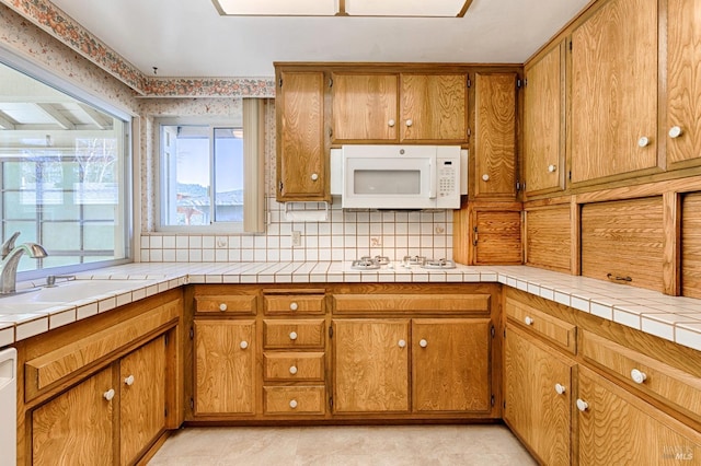 kitchen featuring tasteful backsplash, sink, white appliances, and tile countertops