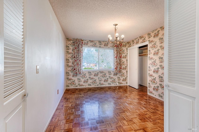 unfurnished bedroom featuring a closet, light parquet flooring, a chandelier, and a textured ceiling