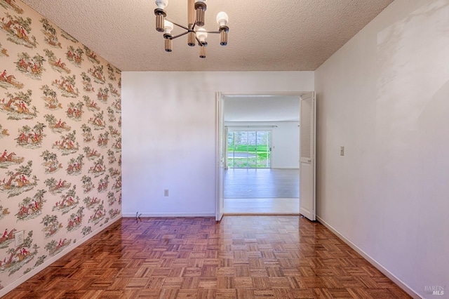 unfurnished room with a chandelier, a textured ceiling, and dark parquet floors