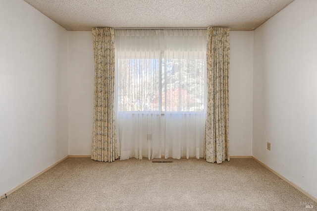 carpeted spare room featuring a textured ceiling