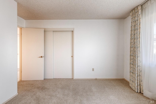 unfurnished bedroom with carpet floors, a textured ceiling, and a closet