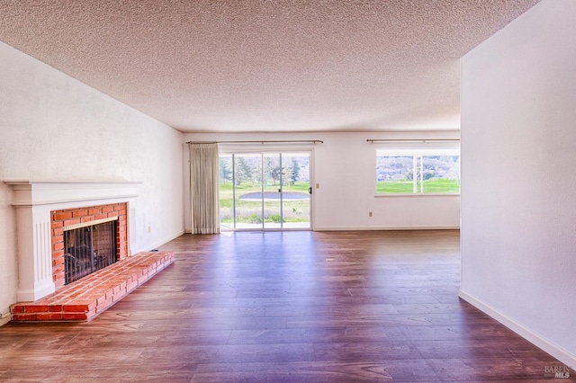 unfurnished living room featuring dark wood-type flooring, a brick fireplace, and a textured ceiling