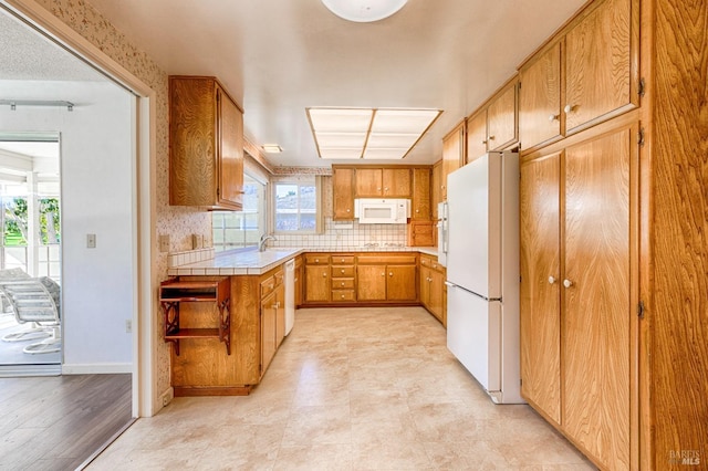 kitchen with tasteful backsplash, white appliances, tile countertops, and sink