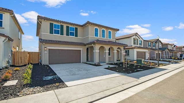 mediterranean / spanish-style house featuring stucco siding, concrete driveway, fence, a garage, and a residential view