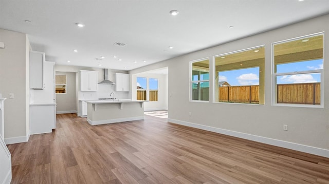 unfurnished living room with recessed lighting, visible vents, light wood-style flooring, and baseboards