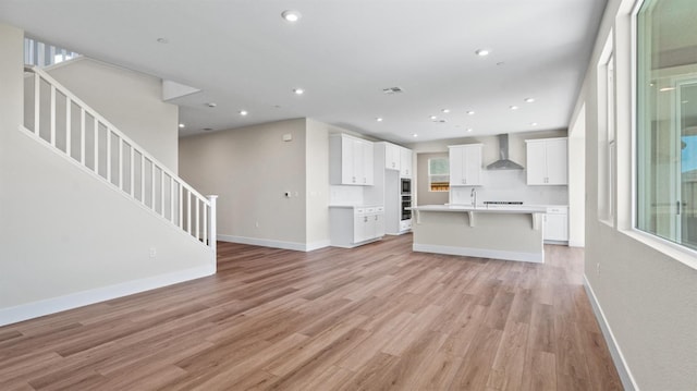 unfurnished living room featuring stairway, recessed lighting, light wood-style flooring, and baseboards