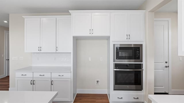 kitchen featuring built in microwave, light countertops, stainless steel oven, and white cabinetry