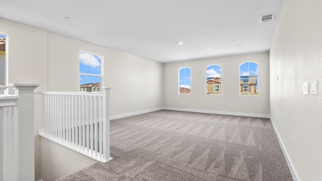 unfurnished room with baseboards, visible vents, and light colored carpet