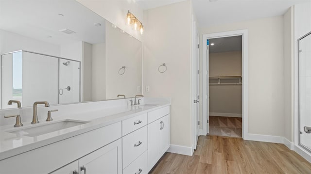 bathroom with a shower stall, a sink, and wood finished floors