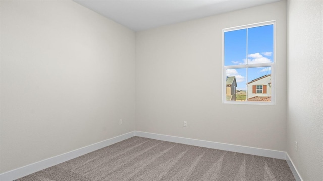 carpeted spare room featuring baseboards