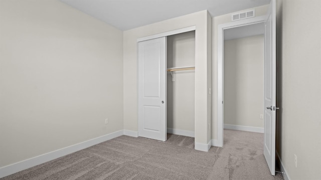 unfurnished bedroom with a closet, visible vents, light carpet, and baseboards