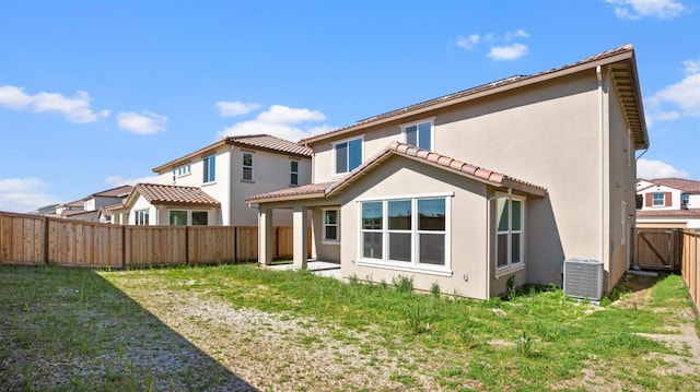 rear view of house with a fenced backyard, a lawn, cooling unit, and stucco siding