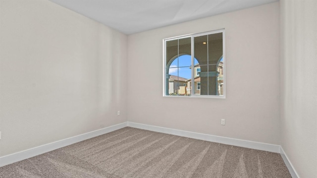 spare room featuring carpet flooring and baseboards