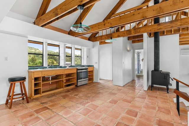 kitchen with high vaulted ceiling, beamed ceiling, a wood stove, hanging light fixtures, and stainless steel gas range