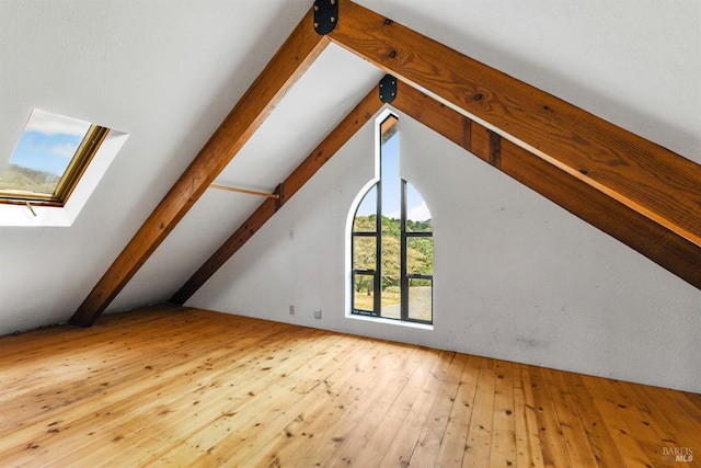 bonus room with hardwood / wood-style flooring and vaulted ceiling with skylight