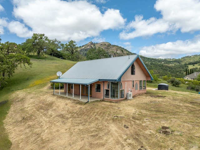 rear view of property with a mountain view and a lawn